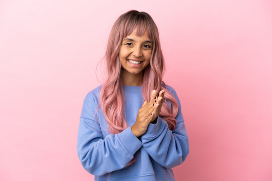 Young mixed race woman with pink hair isolated on pink background applauding after presentation in a conference