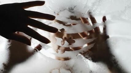 A silhouetted hand presses against a steamy glass pane revealing a persons torso through wiped-away condensation - Powered by Adobe