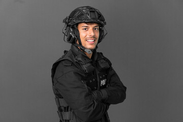 SWAT caucasian man isolated on grey background with arms crossed and looking forward