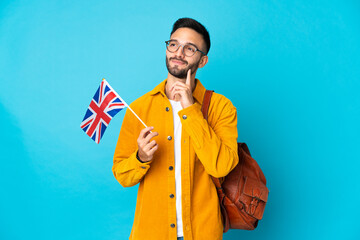 Young caucasian man holding an United Kingdom flag isolated on yellow background thinking an idea...