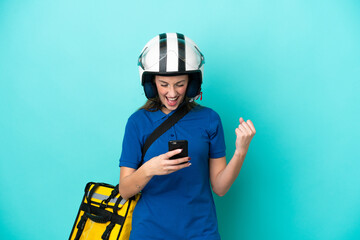 Young caucasian woman with thermal backpack isolated on white background with phone in victory position
