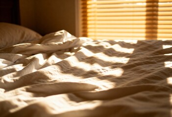 Unmade bed with white rumpled sheets in morning sunlight with shadow of window blinds