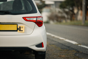 Learner Driver "L Plates" displayed on small white car parked on the side of the road
