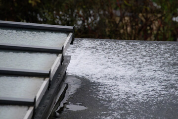 Close-up of flat roof and glass skylight covered in melting snow and ice in winter