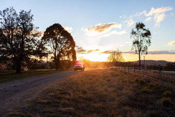 ute traveling up farm gravel driveway road at sunset coming home at the end of the day
