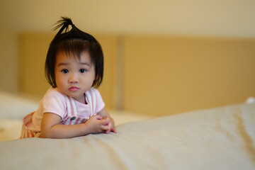 Smiling Baby Lying on Bed in Yellow Onesie