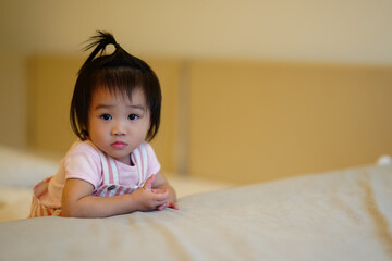 Adorable little girl lying on the bed in soft warm light