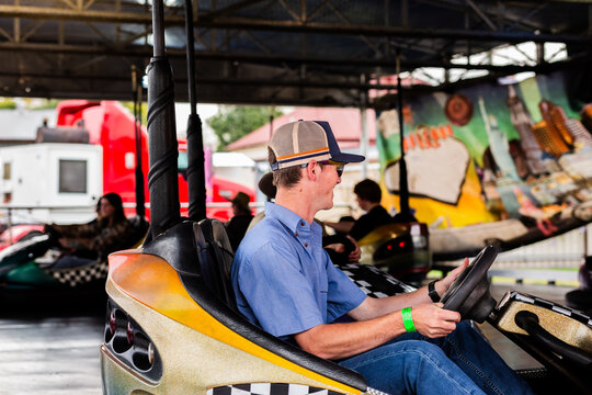 Smiling Australian teen boy driving dodgem car at carnival show ride