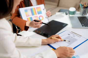 Stylish woman designer working with digital tablet and laptop in a bright studio.