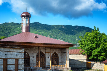 Closer view of a traditional village mosque in Lahij, Azerbaijan, with green mountain scenery.