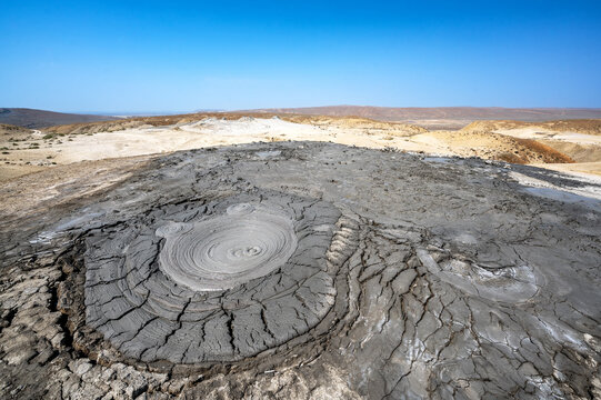 Mud volcano mounds rise across a barren landscape under an open sky in Qobustan, Azerbaijan.