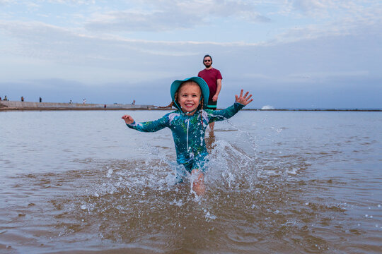 Happy little girl in sun safe swimwear splashing through water in the Newcastle Beach Canoe Pool