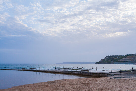 ocean view of rusted posts on coastal pool wall