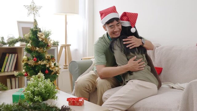 Christmas family xmas couple happy people enjoying home holiday, embracing on comfortable couch, festive decorated tree glowing bright, wrapped presents sitting on coffee table for celebration.