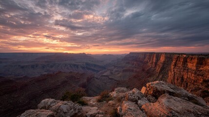 Obraz premium Landscape photograph of the grand canyon at sunset. the sky is filled with orange and pink hues, with the sun setting in the distance.