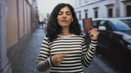 Woman holding czech passport in raised hand and points finger to chest on a cobblestone street with parked car and building facades; identity travel pride.