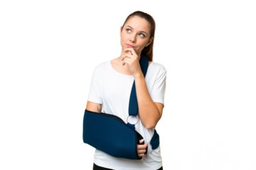 Young blonde woman with broken arm and wearing a sling over isolated chroma key background and looking up