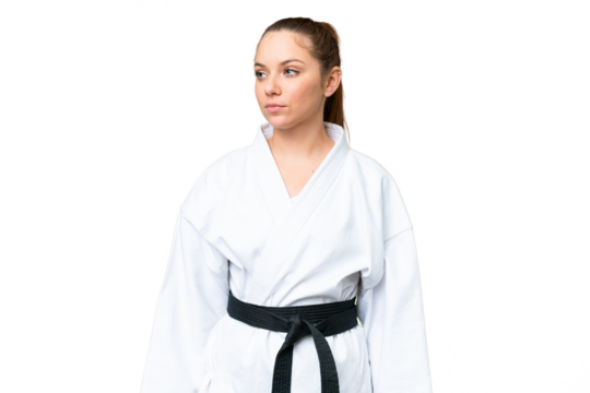 Young blonde woman doing karate over isolated chroma key background looking to the side