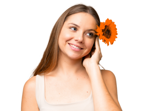 Young blonde woman over isolated chroma key background holding a sunflower while smiling. Close up portrait