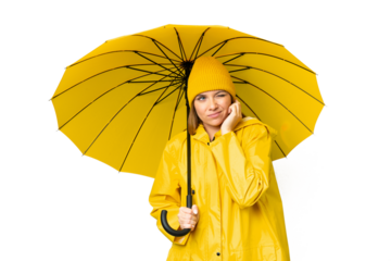 Young blonde woman with rainproof coat and umbrella over isolated chroma key background frustrated and covering ears