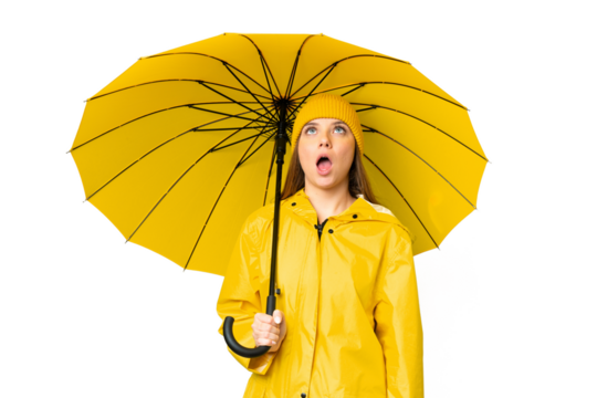 Young blonde woman with rainproof coat and umbrella over isolated chroma key background looking up and with surprised expression