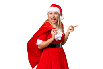 Young blonde woman with christmas hat over isolated chroma key background surprised and pointing finger to the side
