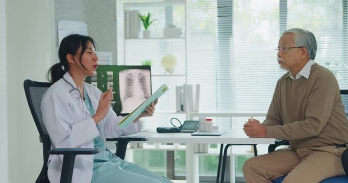 Young Asia female doctor with old man patient use clipboard for consulting, advice and medical expert at desk in health clinic office. Help, appointment support in hospital for diagnosis, physician.