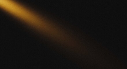 Golden light beam with a subtle grainy gradient effect shining through darkness, creating a cinematic spotlight on a textured black background