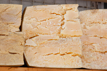 Large pieces of fresh cheese on a shelf at the market.