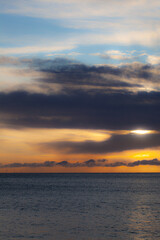 Deep sky of sunset with dark grey clouds and a golden sun shining over the North Sea coast of East Yorkshire, England, UK