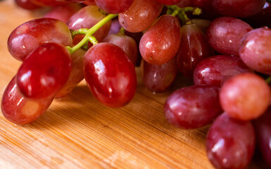 Ruby Grapes on Wooden Board: A vibrant cluster of ripe, ruby-red grapes rests on a rustic wooden board, showcasing their succulent texture and inviting allure. 