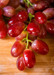 Grapes on Board: A close-up shot of a cluster of ripe, juicy grapes, freshly picked, rests elegantly on a wooden board, ready for the pleasure of eating.