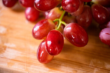 Ruby Grapes on Wood: A cluster of plump, ruby-red grapes sit on a rustic wooden surface. Capturing the perfect blend of color and texture and appetizing appeal
