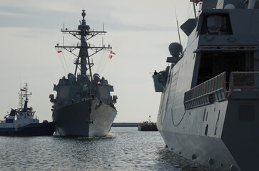 GUIDED MISSILE DESTROYER - US Navy ship maneuvers in the port assisted by a tugboat 