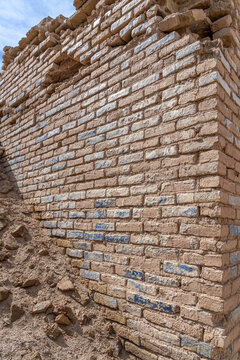 Remnants of a historical brick wall stand against a clear blue sky in Uruk, Iraq, showcasing ancient craftsmanship and heritage