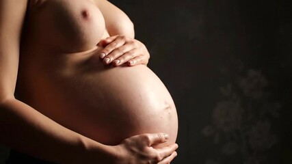 Close up of Nude Pregnant Woman Cradling Belly in Dramatic Light against Floral Texture Background Tenderly Holding Baby Bump in Anticipation of Motherhood and Upcoming Labor Process