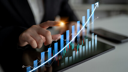 A business professional uses a tablet to analyze financial growth with a candlestick graph, illustrating positive trends in a modern office environment. Scalp