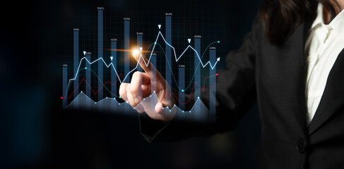 Businesswoman interacts with a digital display showcasing various graphs and charts, emphasizing data analysis and technology in a professional office environment. Scalp