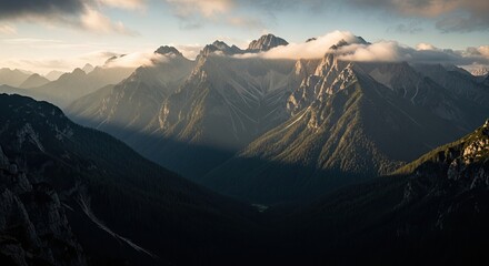 Breathtaking panoramic view of a majestic mountain range at sunrise, where golden light kisses the rocky peaks and clouds drift over a deep, shadowed pine forest