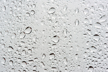 Abstract closeup of rain droplets resting on smooth reflective surface with tiny sparkles and soft reflections capturing quiet weather moment
