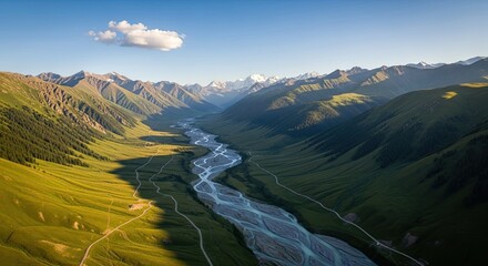 Spectacular aerial view of a braided river winding through a vast green valley surrounded by majestic mountains during a serene golden hour sunrise