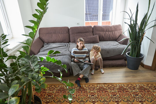 Cozy living room scene with family reading time on comfortable sofa - Powered by Adobe