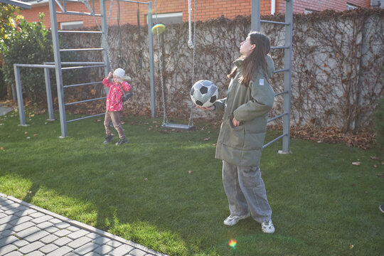 Children playing outdoors with soccer ball on sunny day in backyard playground