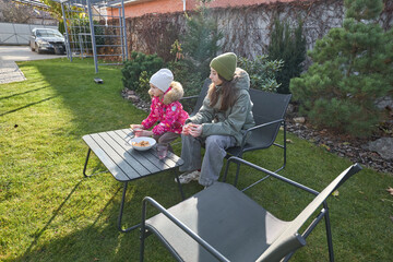 Two girls relaxing on a sunny day in the garden with snacks and drinks