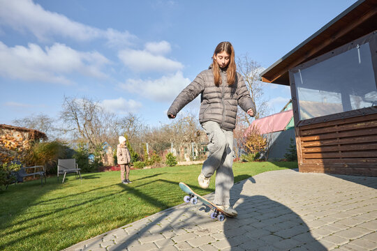 Teenage girl practicing skateboard tricks outdoors on a sunny day