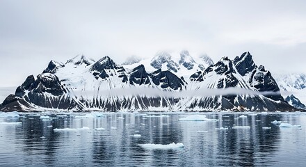 Majestic panoramic view of a snow-covered mountain range with jagged peaks rising from a cold polar sea filled with floating icebergs under a moody, overcast sky