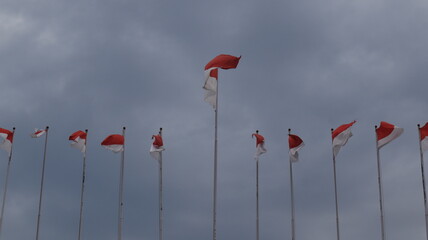 The Indonesian flag, Red and White, flies on a pole against a blue sky background.