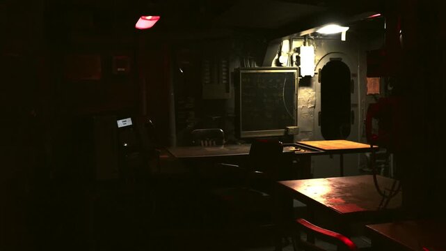 Moody, low-light interior of a ships navy war room featuring desks, communication consoles, and operational equipment. Cinematic military atmosphere suited for documentaries, spy and defence. 