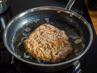 Frying breaded chicken cutlet in frying pan	