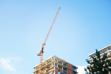 A tall crane is building a tall skyscraper to the very clouds